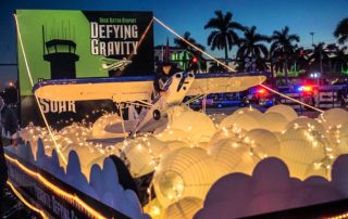 Boca Raton Holiday Parade BRAA float Defying Gravity shows witch on top of Cessna 172