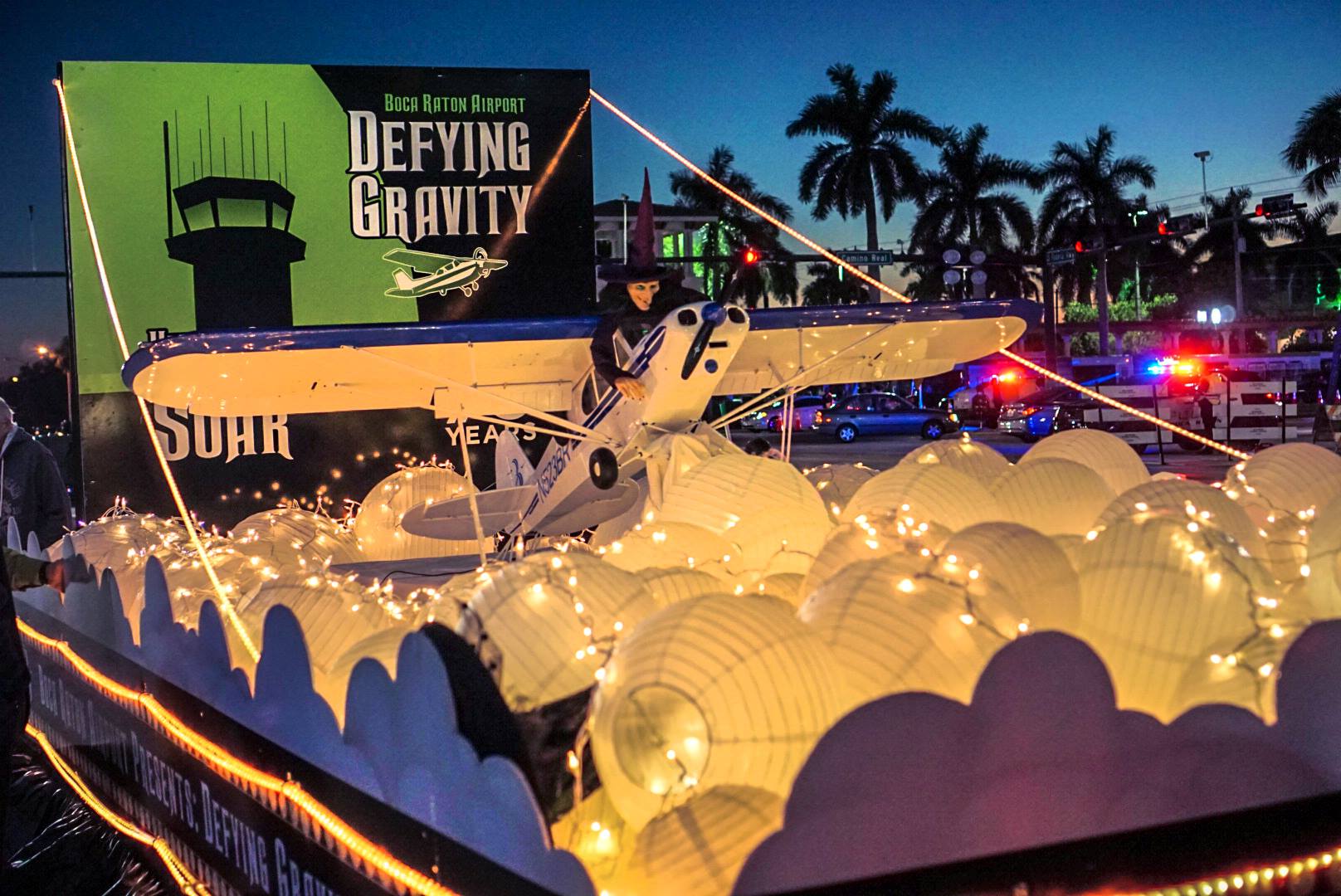 Boca Raton Holiday Parade BRAA float Defying Gravity shows witch on top of Cessna 172