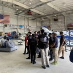 Boynton Aerospace Science Academy students gather in a hangar, listening to instructor
