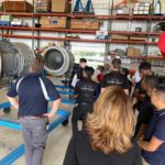 Students examine jet engines in hangar at Reliable Jet