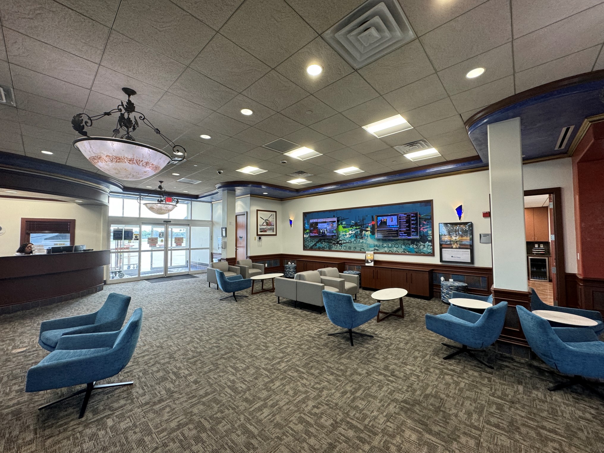 Room with blue chairs, pendant lights and a kiosk