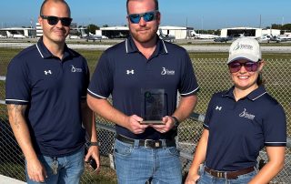 Three Persons posing with a plaque